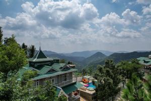 a building with a green roof with a swimming pool at SaffronStays StoneVilla in Shimla