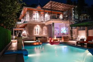 a swimming pool in front of a house at night at SaffronStays StoneVilla in Shimla