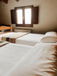 a group of three beds in a room with a window at Alberg rural torre del baró in Sant Llorenç de Morunys