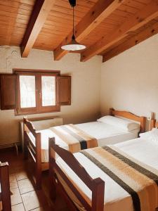 a bedroom with three beds in a room with wooden ceilings at Alberg rural torre del baró in Sant Llorenç de Morunys +80 photos