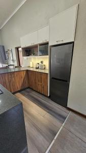 a kitchen with a black refrigerator and wooden floors at Pine View Guesthouse Graskop in Graskop