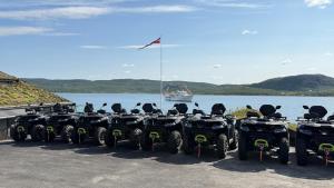 a row of atvs parked next to a body of water at Aurora Sea Lodges AURORAHUT in Herjenes
