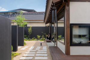 a person sitting on a bench outside of a house at 한옥스테이 서유재 in Ch'unch'ŏn-yŏk