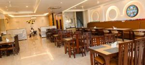 a restaurant with tables and chairs and a woman sitting in the background at The Pearl Hotel Rampur in Rāmpur