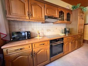 a kitchen with wooden cabinets and a microwave at Ferienwohnung Heidi in Annaberg-Buchholz