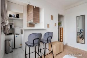 a kitchen with two blue chairs and a kitchen with a refrigerator at Bright Studio Near Paris & Disneyland in Neuilly-Plaisance
