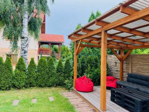 a wooden pergola with a bench and red bags at Penzion Larion in Kráľová Lehota