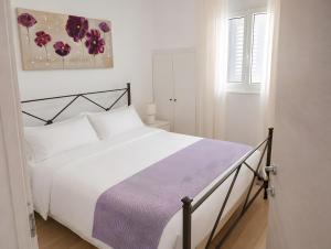 a bedroom with a white bed with a purple blanket at Marea Blanca in Porto Cesareo