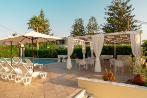 Eine Terrasse mit Stühlen und Sonnenschirmen neben einem Pool in der Unterkunft Creta Aquamarine Hotel in Platanes
