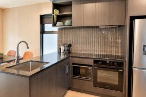 a kitchen with a sink and a stainless steel refrigerator at Relax on Remarkable in Queenstown