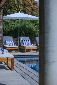 two lounge chairs and an umbrella next to a pool at Villa Scappà Porticcio - Piscine & vue mer in Grosseto-Prugna