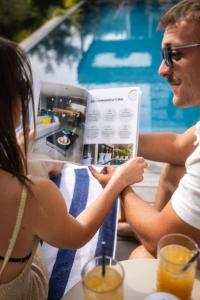 a man and woman sitting at a table reading a magazine at Villa Scappà Porticcio - Piscine & vue mer in Grosseto-Prugna +81 photos