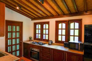 a kitchen with a stove and a microwave and windows at Cathaya Private Pool Villa - Limasan Padi in Langkawi Intl