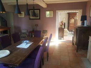 a dining room with a wooden table and purple chairs at Chambre D'hôtes De La Vaine in Cartelègue