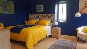a blue bedroom with a bed with a yellow blanket at Chambre D'hôtes De La Vaine in Cartelègue