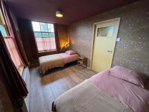 a room with two beds and a door to a bedroom at De Noorderzon in Benningbroek