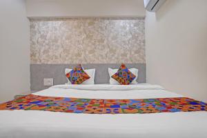 a bed with a colorful comforter and pillows on it at FabHotel Sky Inn I in Ahmedabad