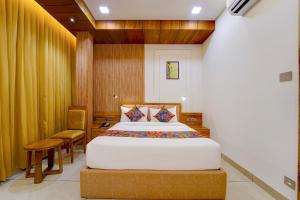a bedroom with a bed and a chair at FabHotel Prime Hash Four in Ernakulam