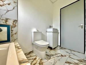 a bathroom with a white toilet and a marble floor at Number 15 Jadde Apartments in Sandton +15 photos