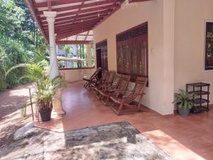 a porch with a bunch of chairs and a table at Miriswaththa resort in Deniyaya