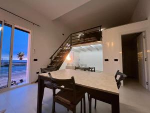 a dining room with a table and chairs and a spiral staircase at Vista Mare in Cipressa