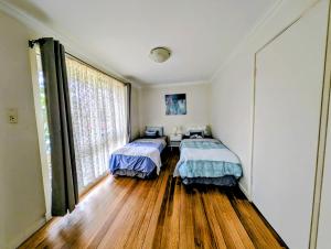 two beds in a room with wooden floors and a window at Star House in Mitcham