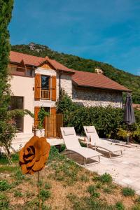 ein Haus mit zwei Liegestühlen und einem Sonnenschirm in der Unterkunft L'écrin des granges in Culoz