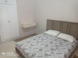 a bedroom with a bed with a gray and white comforter at Appartement Bizerte Nord in Bizerte