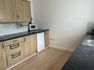 a kitchen with wooden cabinets and a white microwave at Comfortable room in Newbridge