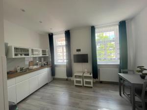 a kitchen with white cabinets and a table and windows at Apartman cheb in Cheb