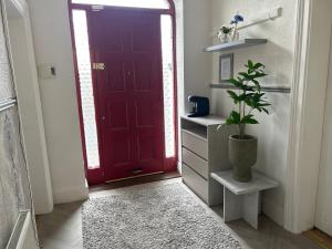 a red door in a hallway with a potted plant at Comfortable room in Newbridge