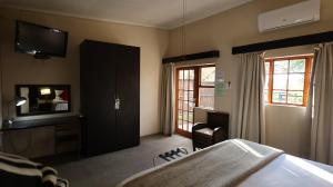 a bedroom with a bed and a tv on the wall at Lanseria Country Estate in Lanseria