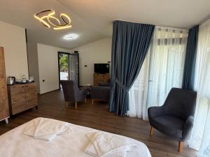a bedroom with a bed and chairs and a television at Gul Pension in Faralya