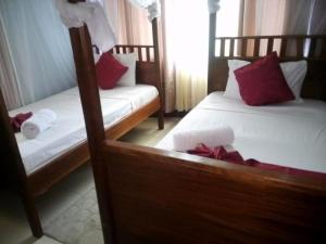 a bedroom with two beds with red pillows at sunset suswa apartment in Mombasa