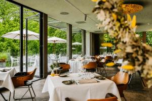 a restaurant with white tables and chairs and windows at Hotel Winselerhof by Flow in Landgraaf