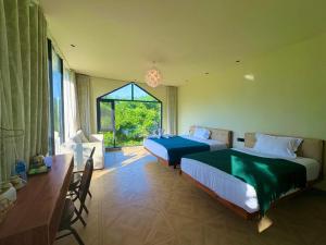 a bedroom with two beds and a desk and a window at Vangvieng Lina hotel in Vang Vieng +120 photos