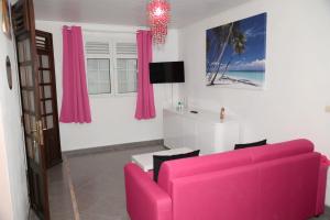 a living room with a pink couch and pink curtains at Résidence Fruit de la Passion Rose in Sainte-Anne