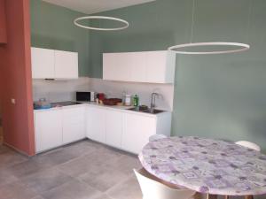 a kitchen with white cabinets and a table with chairs at Ostello Postumia in Torre deʼ Picenardi