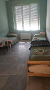 a room with three beds and a table and windows at Ostello Postumia in Torre deʼ Picenardi