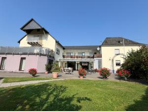 a large pink building with a balcony and a yard at Weingut Lindenhof in Thörnich