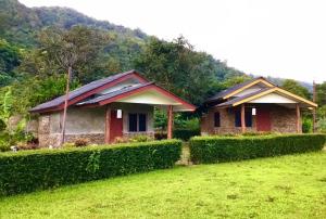 two small houses in a field with bushes at ดอยล้อมฟาร์มสเตย์ in Ban Muang Kut