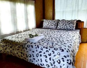 a bed with a black and white comforter and pillows at ดอยล้อมฟาร์มสเตย์ in Ban Muang Kut