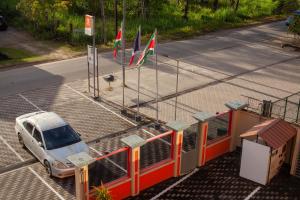 a car parked in front of a fence with flags at Barolena Hotel en appartement in Paramaribo
