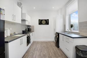 a kitchen with white cabinets and a clock on the wall at Spacious 4BR retreat Eden Vale by Stay With Us in Sunderland