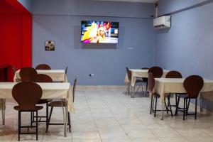 a dining room with tables and a tv on the wall at Barolena Hotel en appartement in Paramaribo