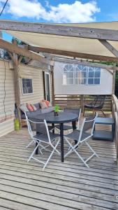 a patio with a table and chairs on a deck at Mobile-home 4, 6 places in Quédillac
