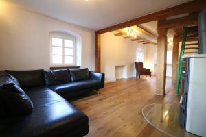 a living room with a black leather couch and wooden floors at Milchhäusle in Söllingen +1 photo