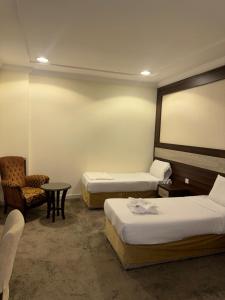 a room with two beds and a chair and a table at فندق شعاع النزهة - مكة المكرمة in Mecca +54 photos