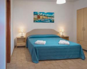 a bedroom with a bed with blue sheets and two lamps at Testa di Monaco - Basic Beach Accommodations in Capo dʼOrlando