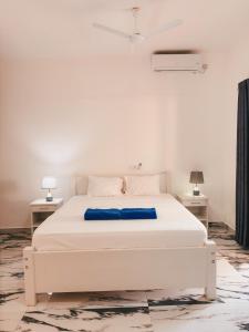 a white bed in a white room with two tables at Diani Dream luxury apartment in Diani Beach +22 photos